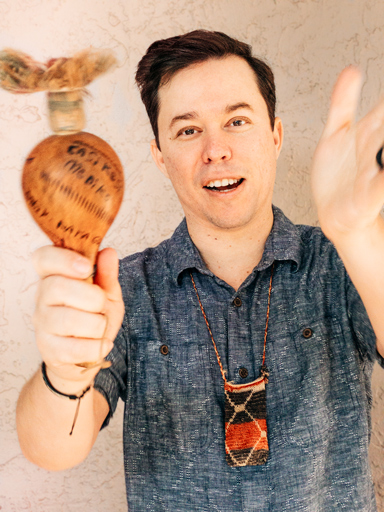 Close-up photo portrait of Frank, shaking a traditional Indigenous maraca.