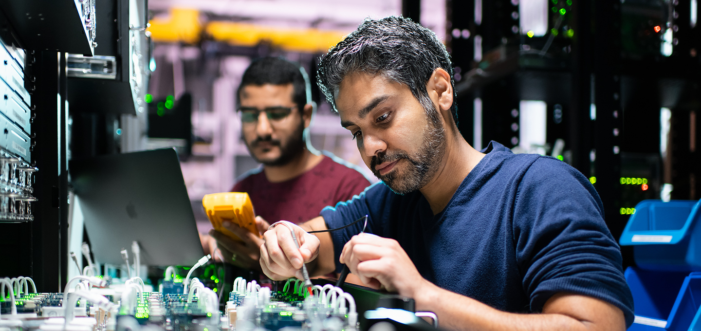 To Apple-teknikere, der arbejder med iPhone-komponenter i et laboratorie