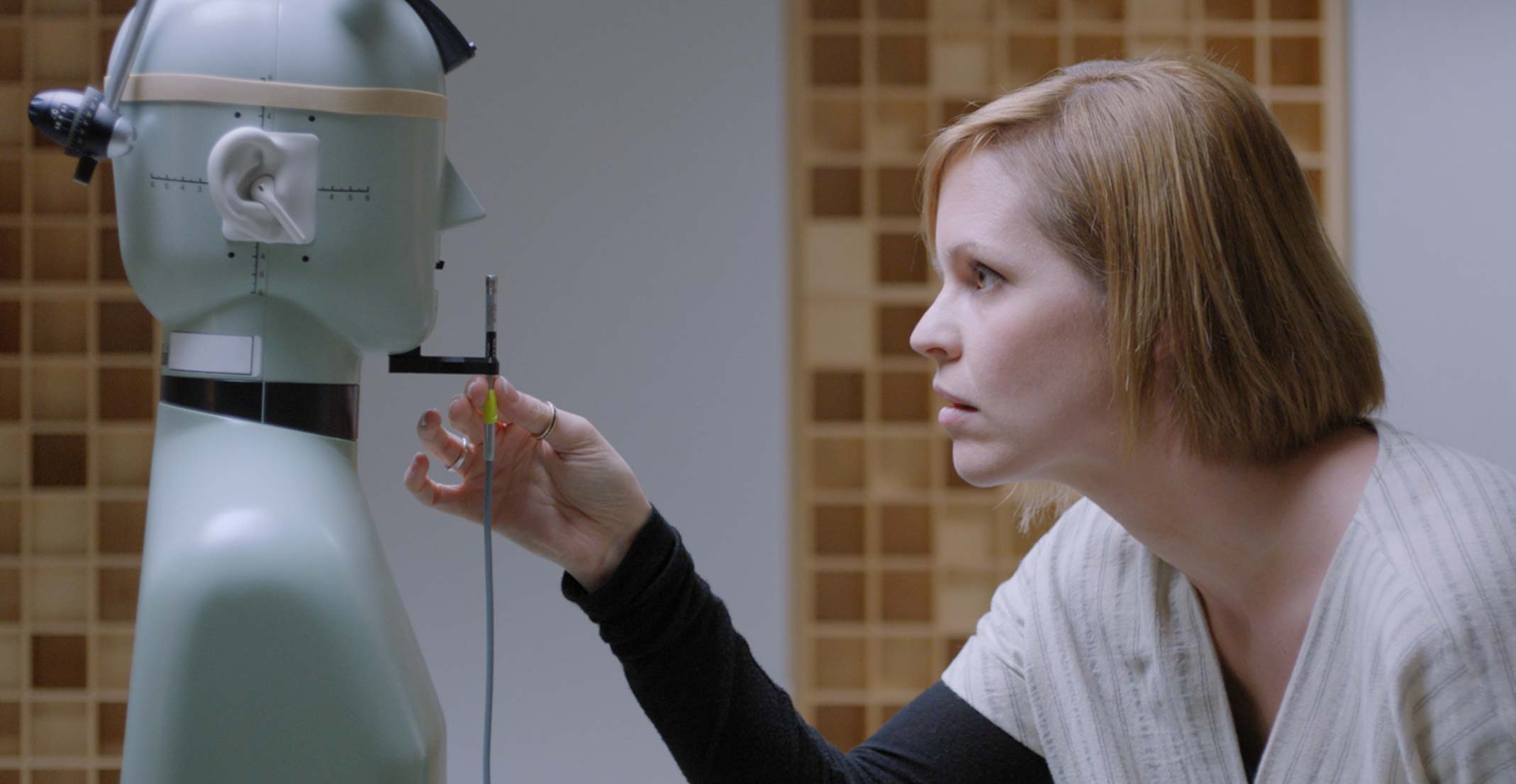Suzie ผู้จัดการกลุ่มสร้างต้นแบบระบบเสียงที่ Apple กำลังปรับไมโครโฟนหน้าหุ่นจำลองในห้องปฏิบัติการวิศวกรรมในคูเปอร์ติโน