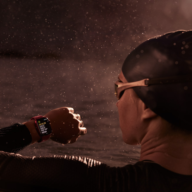 泳者在泳池中查看 Apple Watch 的圖片。