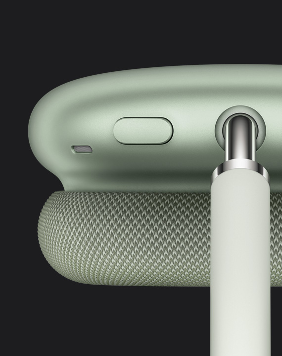Yeşil renkli AirPods Max ve taç kısmı bağlantı noktasınının yanında ve kulaklık kapağının üst kısmında yer alan gürültü denetimi düğmesinin detaylı görünümü.
