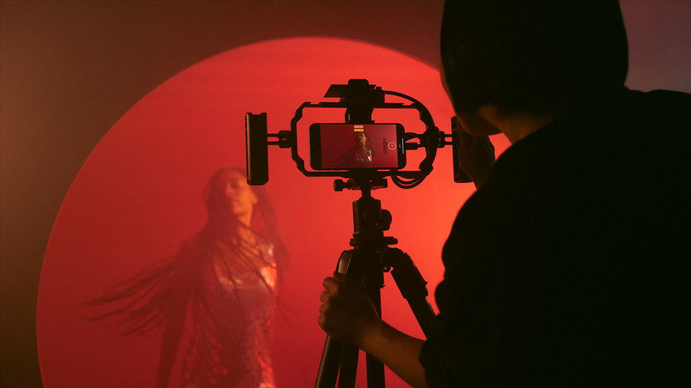 En bild på någon som har en iPhone på ett stativ för att filma en färgglad video med en kvinna
