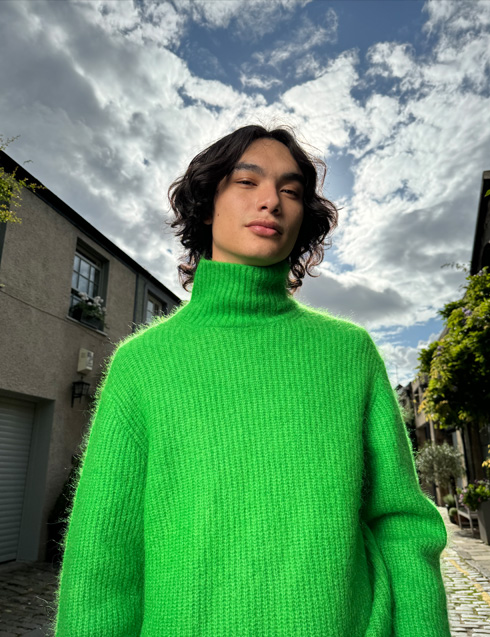 Foto tirada com o iPhone 15 Pro que mostra uma pessoa vestindo um suéter de cor brilhante e retrata seu tom de pele com precisão.