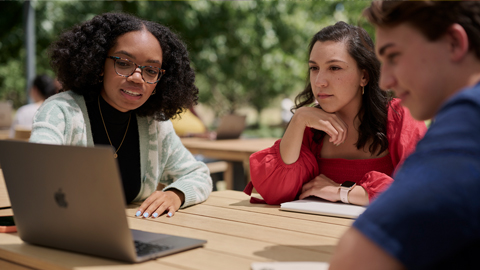 Zwei Studentinnen sitzen draußen auf dem Apple Campus.