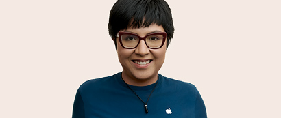Empleada de Apple Retail con cabello corto y lentes, sonríe a la cámara.
