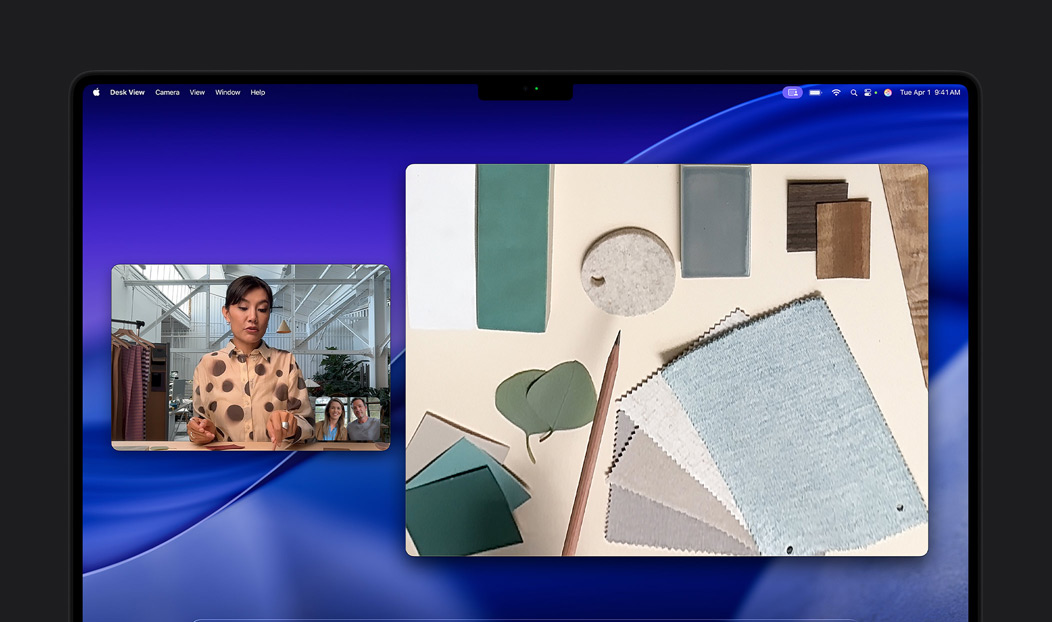 Videochiamata su MacBook Pro con una donna che usa la funzione Panoramica Scrivania per mostrare a due persone il suo spazio di lavoro pieno di tessuti; con Panoramica Scrivania riesce a mostrare contemporaneamente il proprio volto e lo spazio di lavoro