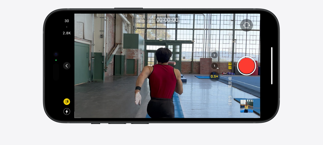 圖片展示 iPhone 15 Pro 拍攝動作模式影片，體操選手光線明亮的大型室內空間跑步。