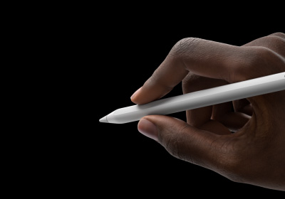 A user's hand holds Apple Pencil Pro in a writing position. The tip is pointed towards an interface showing a new tool palette.