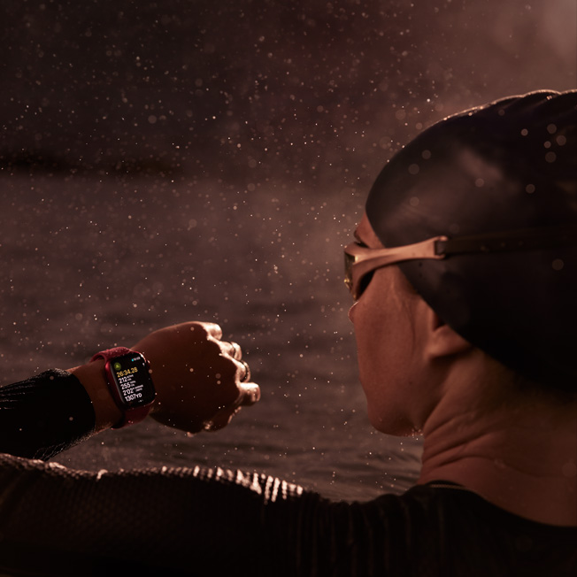Zdjęcie osoby pływającej w basenie, spoglądającej na Apple Watch.