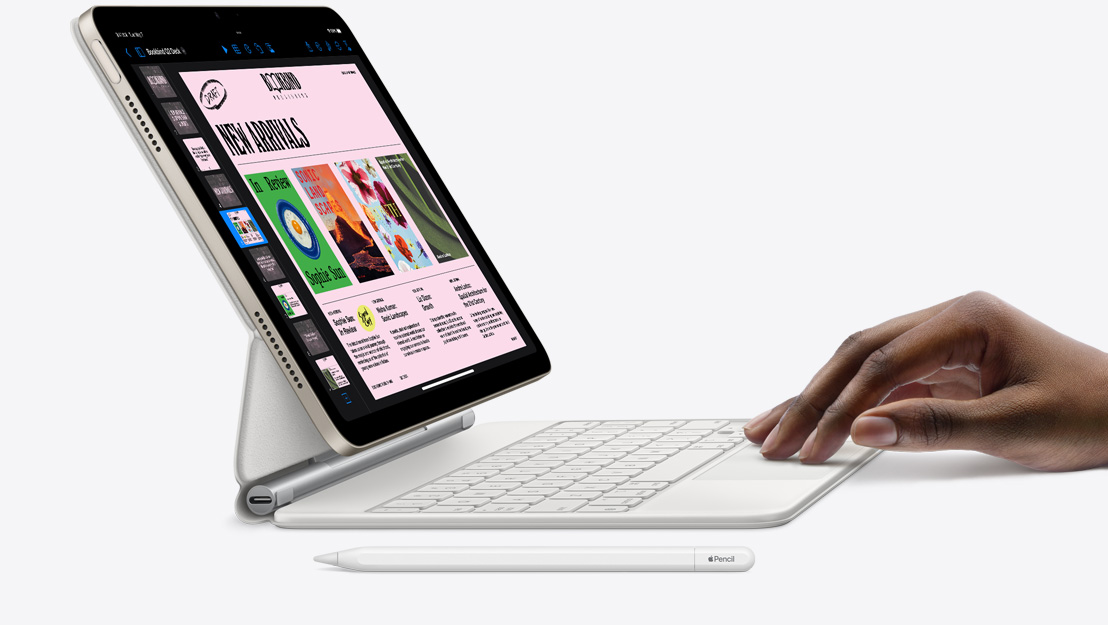 Widok z boku na iPada Air pokazującego aplikację Keynote. Urządzenie jest połączone z klawiaturą Magic Keyboard. Na gładziku znajduje się dłoń, a obok widać Apple Pencil.