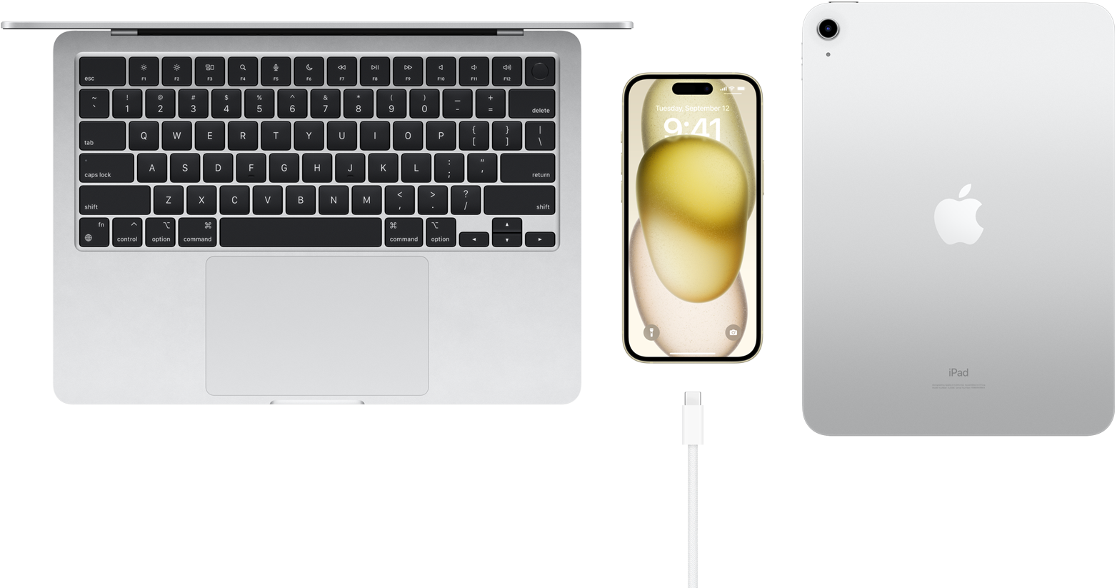 Tampilan atas MacBook Pro, iPhone 15 dengan konektor USB-C, dan iPad