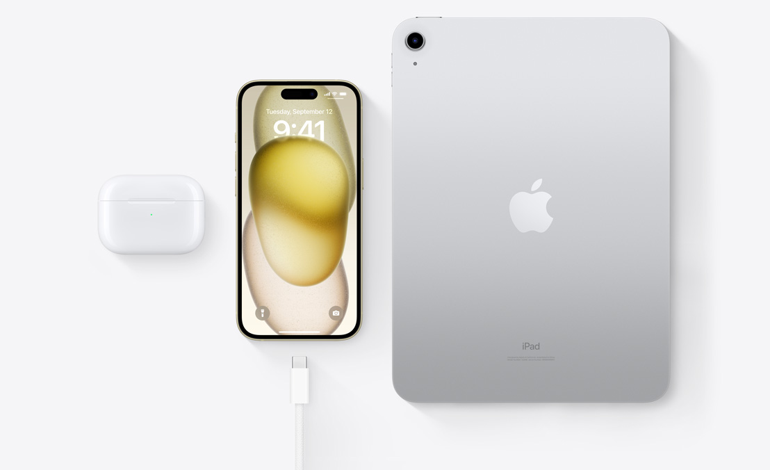 Изглед отвисоко на AirPods Pro, iPhone 15 и iPad с USB-C конектор, за да се види, че и трите устройства могат да се зареждат с един и същ USB-C кабел.