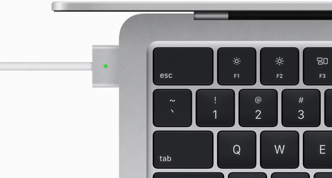 Pohled shora na MagSafe kabel zapojený do stříbrného MacBooku Air