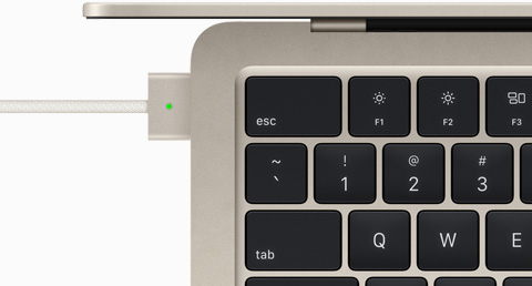Billede ovenfra af et MagSafe-kabel, som er tilsluttet en MacBook Air i farven stjerneskær