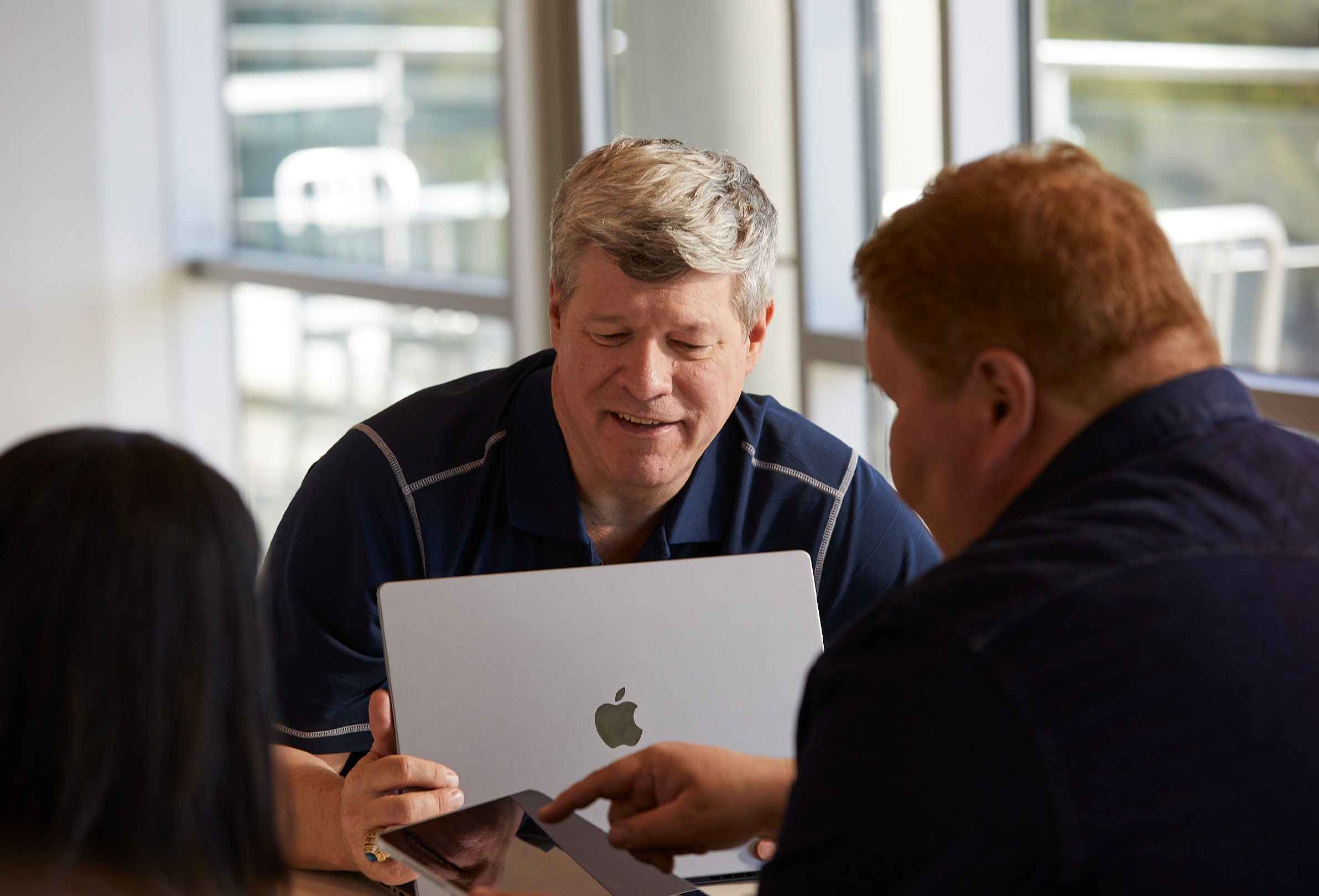 Três funcionários da Apple usam um MacBook e um iPad para colaborar.