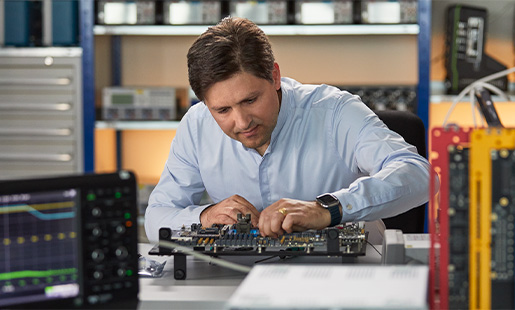 Greg, der arbejder i et hardware engineering-laboratorie, omgivet af udstyr til at teste chips.