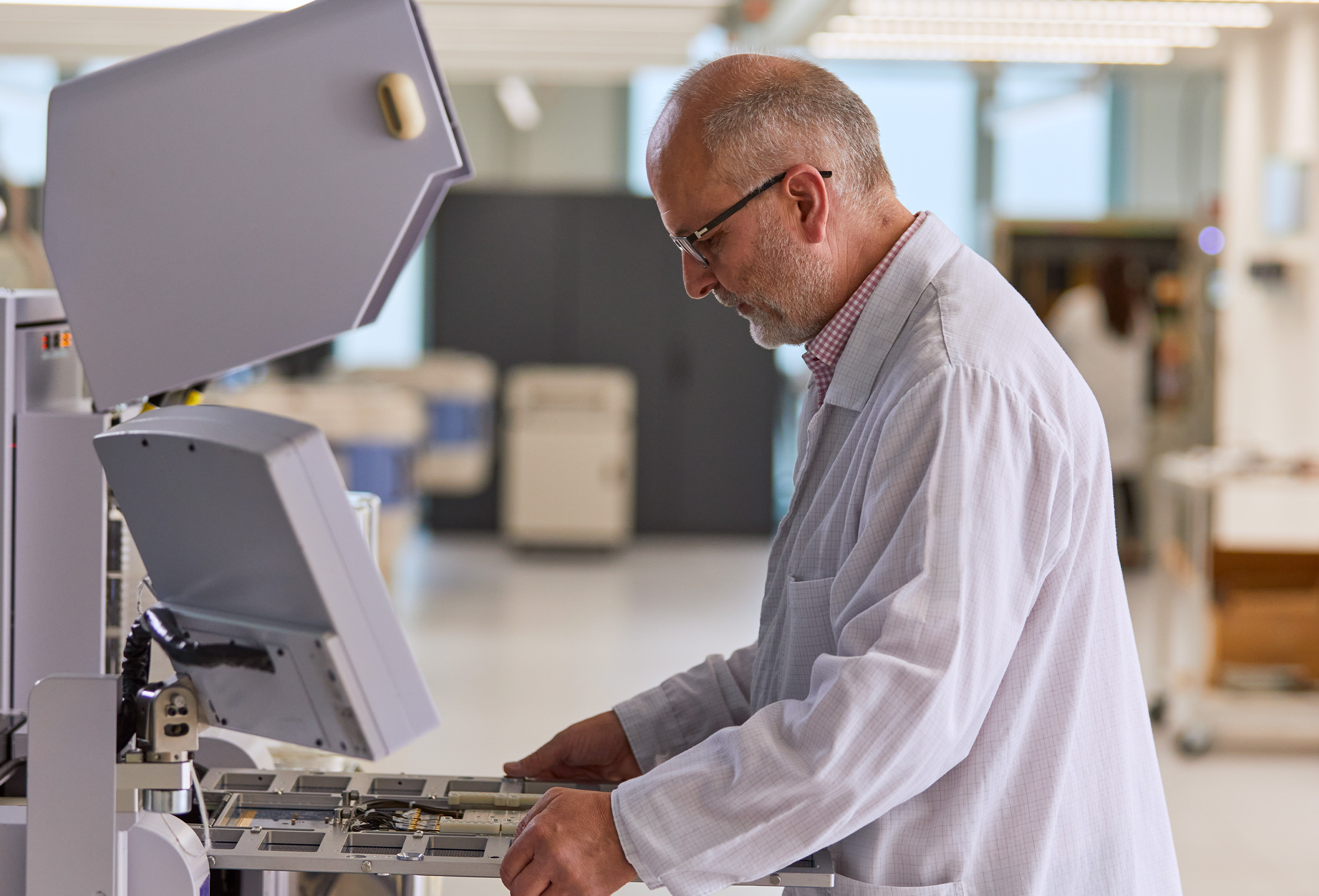 Ein Apple Mitarbeiter in einem weissem Laborkittel arbeitet an einem Messgerät. 
