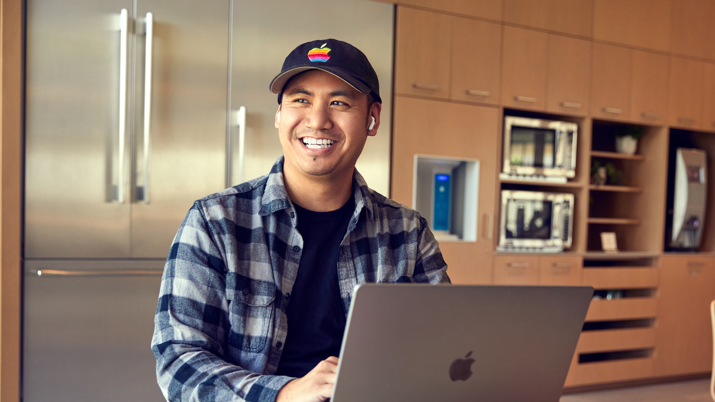 Uśmiechnięty mężczyzna zatrudniony przez Apple w San Diego pracujący na swoim laptopie.