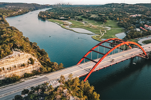 Luchtfoto van een rivier en brug in Austin, met de stad op de achtergrond.