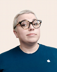 Empleado de Apple Retail con cabello corto y lentes sonríe a la cámara.