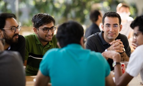  一群 Apple 實習生坐在 Caffè Macs 的桌邊交談。