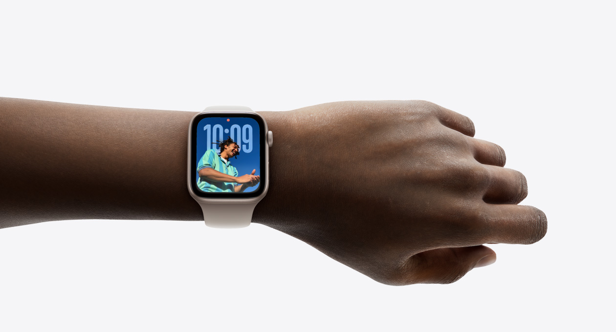 Närbild på Apple Watch i roséguld med armband i gummi på en persons handled för att visa upp den nya designen med Liquid Glass