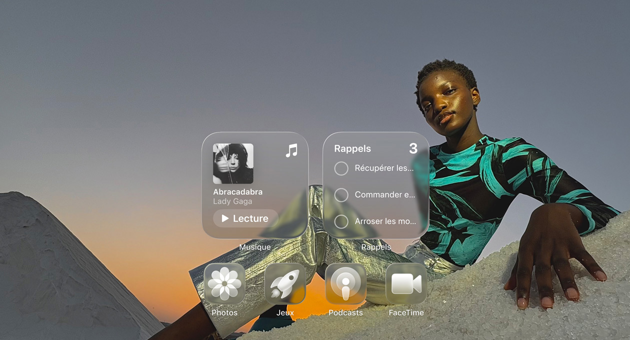 Écran en Liquid Glass avec des icônes d’app transparentes, comme Apple Music, Rappels, Photos, Jeux, Podcasts et FaceTime qui se réfractent contre le fond d’écran