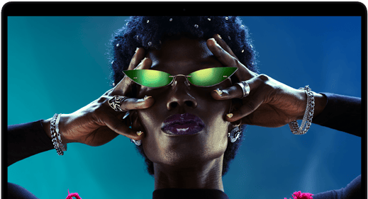 شاشة ملونة على MacBook Pro تُظهر شخصاً يتفاعل بحماس مع الجمهور في إحدى الحفلات، ما يبرز حيوية شاشة ريتنا ليكويد XDR النابضة بالحياة