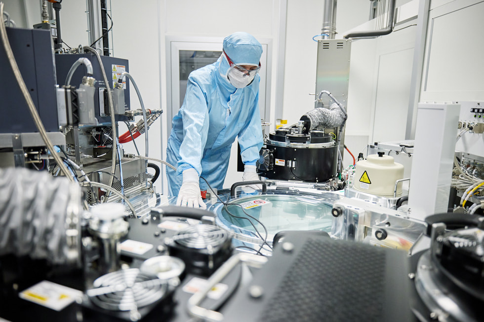 Een medewerker in beschermende kleding is machines aan het controleren in een laboratorium-achtige ruimte bij TRUMPF Ulm.