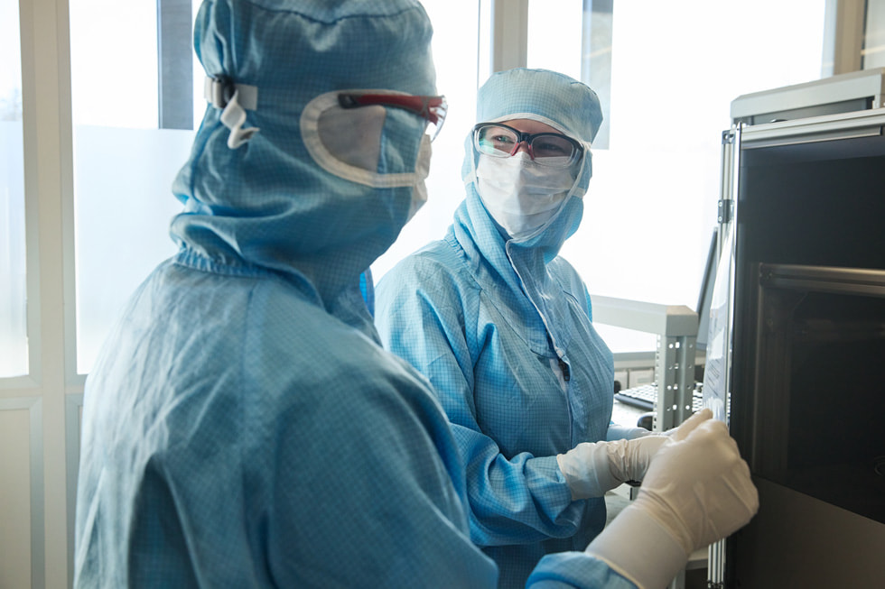 Deux techniciens de l’entreprise TRUMPF Ditzingen portant des équipements de protection se regardent mutuellement dans un laboratoire.