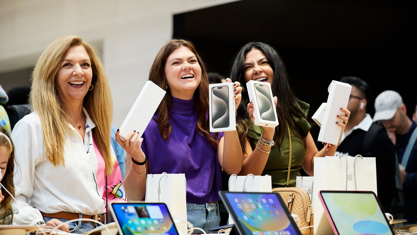 Des clientes souriantes montrent leurs achats de produits de la gamme iPhone 15 dans la boutique Apple Fifth Avenue à New York.