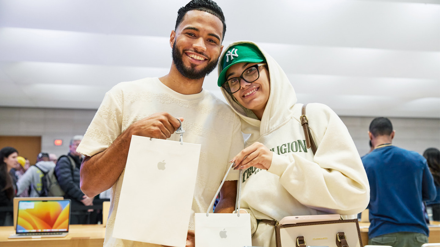 Hai khách hàng đang cầm túi đựng sản phẩm mới mua bên trong cửa hàng Apple Fifth Avenue ở Thành Phố New York.