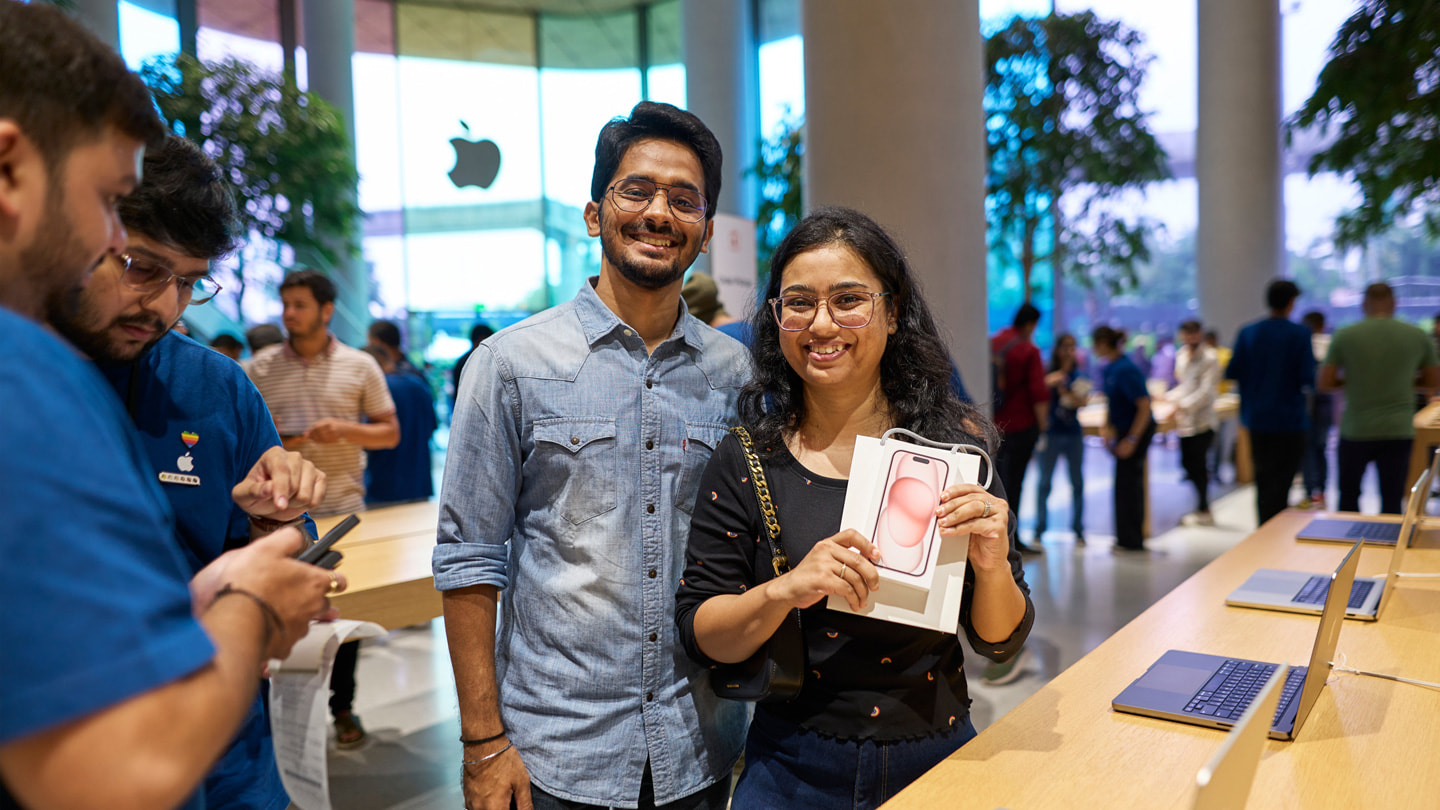 Dwoje klientów pozuje do zdjęcia razem z iPhonem 15 kupionym w sklepie Apple BKC w Mumbaju.