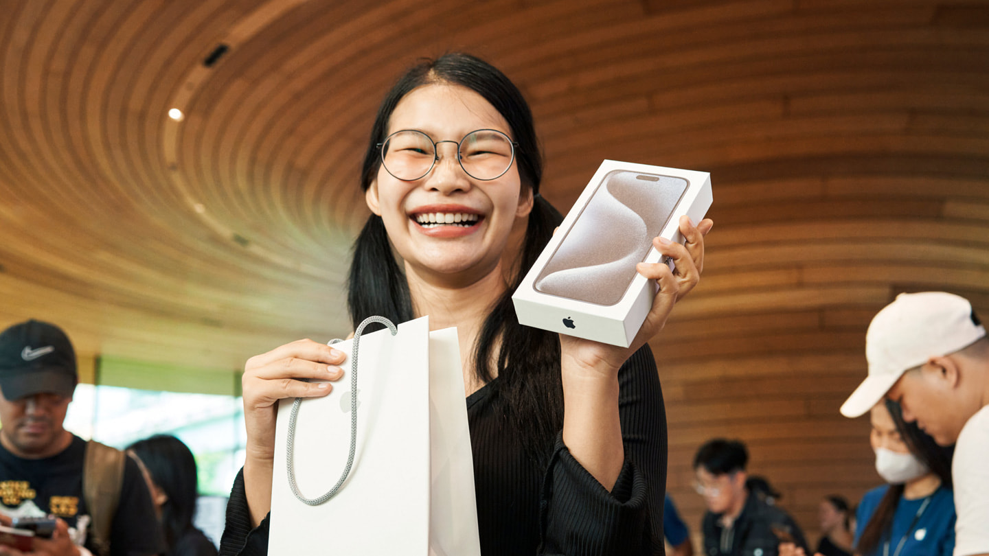 Ein:e Kund:in zeigt stolz das neu gekaufte iPhone 15 Pro Max im Apple Central World in Bangkok.