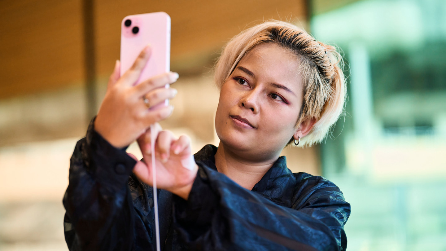 Une cliente prend un selfie avec un iPhone 15 Plus rose dans la boutique Apple Central World à Bangkok.