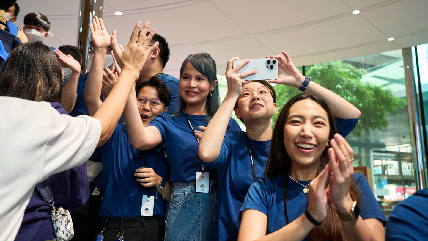 Medarbetare på Apple Central World firar när de första iPhone 15-kunderna kommer in i butiken.