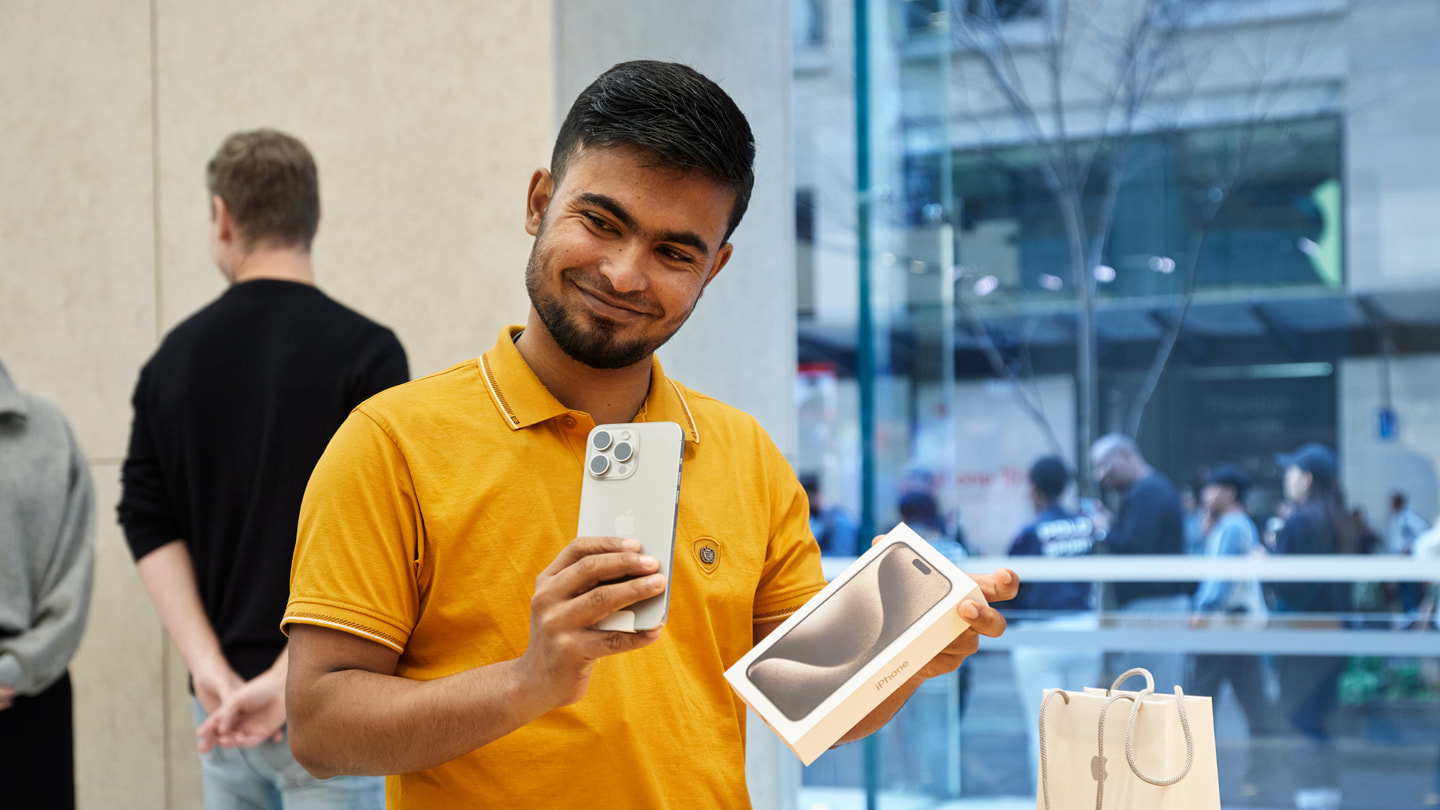 Ein glücklicher Kunde hält ein neues iPhone 15 Pro im Apple Sydney, Australien, hoch.