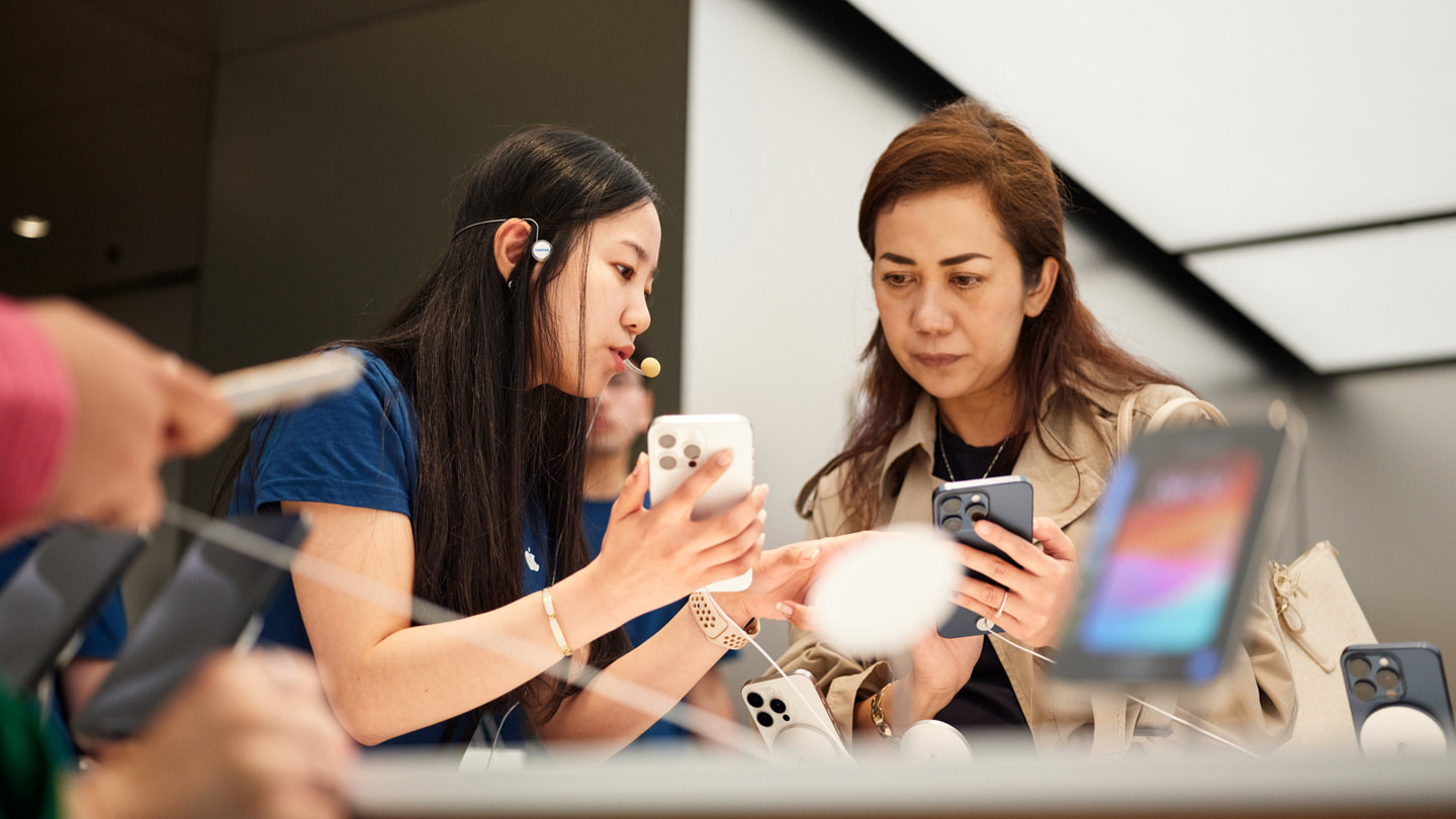 Een medewerker van Apple helpt een klant bij de aanschaf van iPhone 15 Pro bij Apple Sydney, Australië.