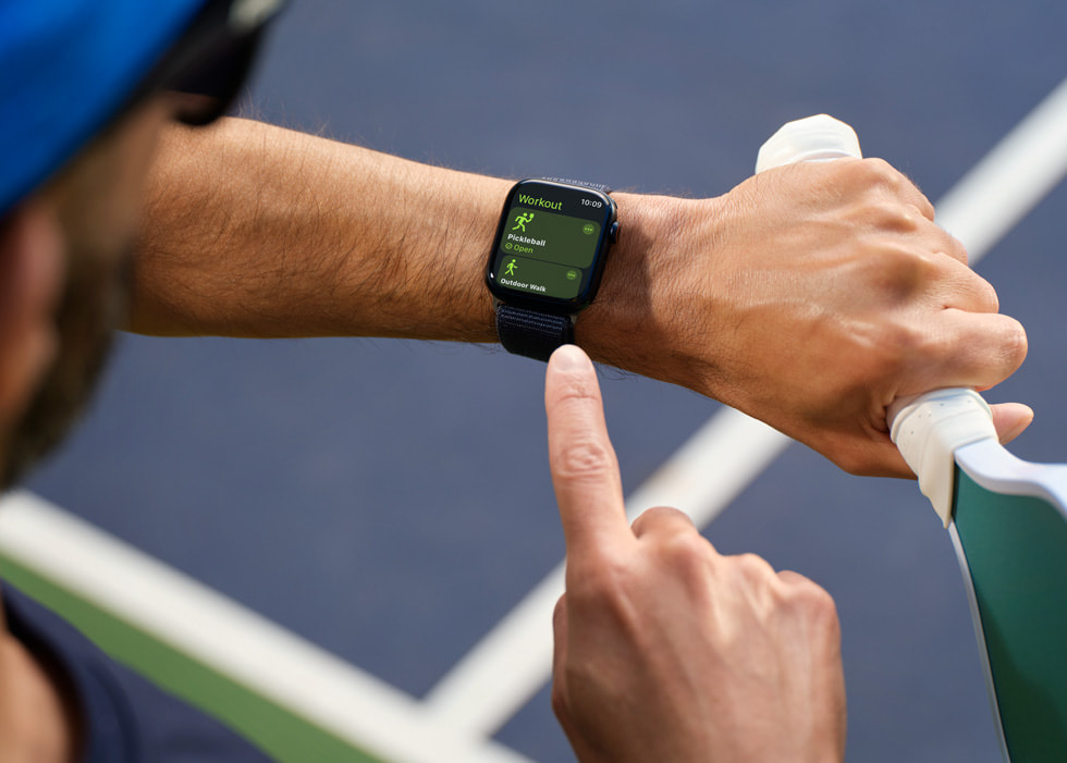 A pickleball player looking at Apple Watch is shown.