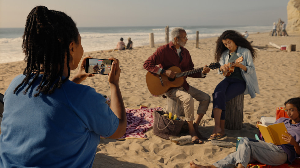 Osoba nagrywająca na plaży wideo przestrzenne za pomocą iPhone’a 15 Pro.