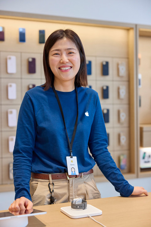 Apple 弘大零售店內一位微笑著的 Apple 團隊成員。