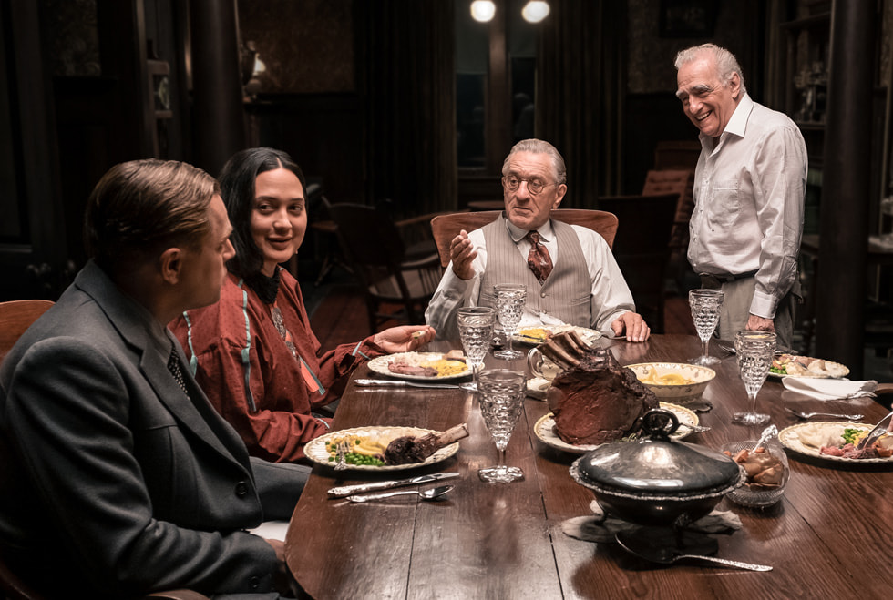 Una imagen del rodaje de «Los asesinos de la luna», que muestra a Leonardo DiCaprio, Lily Gladstone, Robert De Niro y Martin Scorsese alrededor de una mesa con comida.