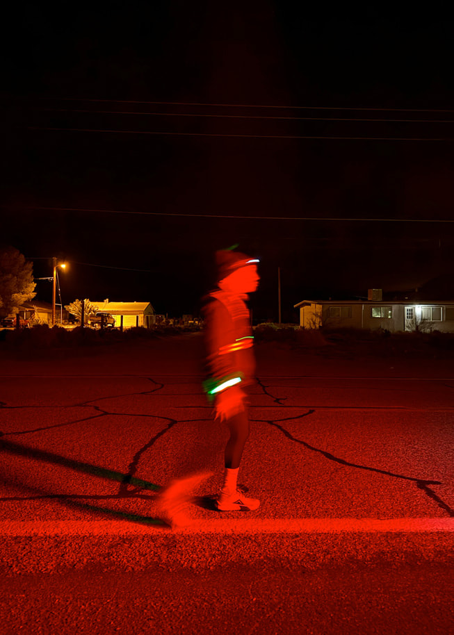 Karanlık yolda yansıtıcı ekipman giymiş bir koşucu.