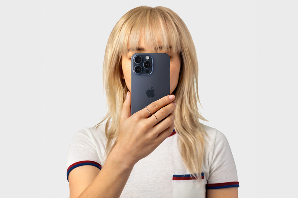 A person holds an iPhone 15 Pro to their face.