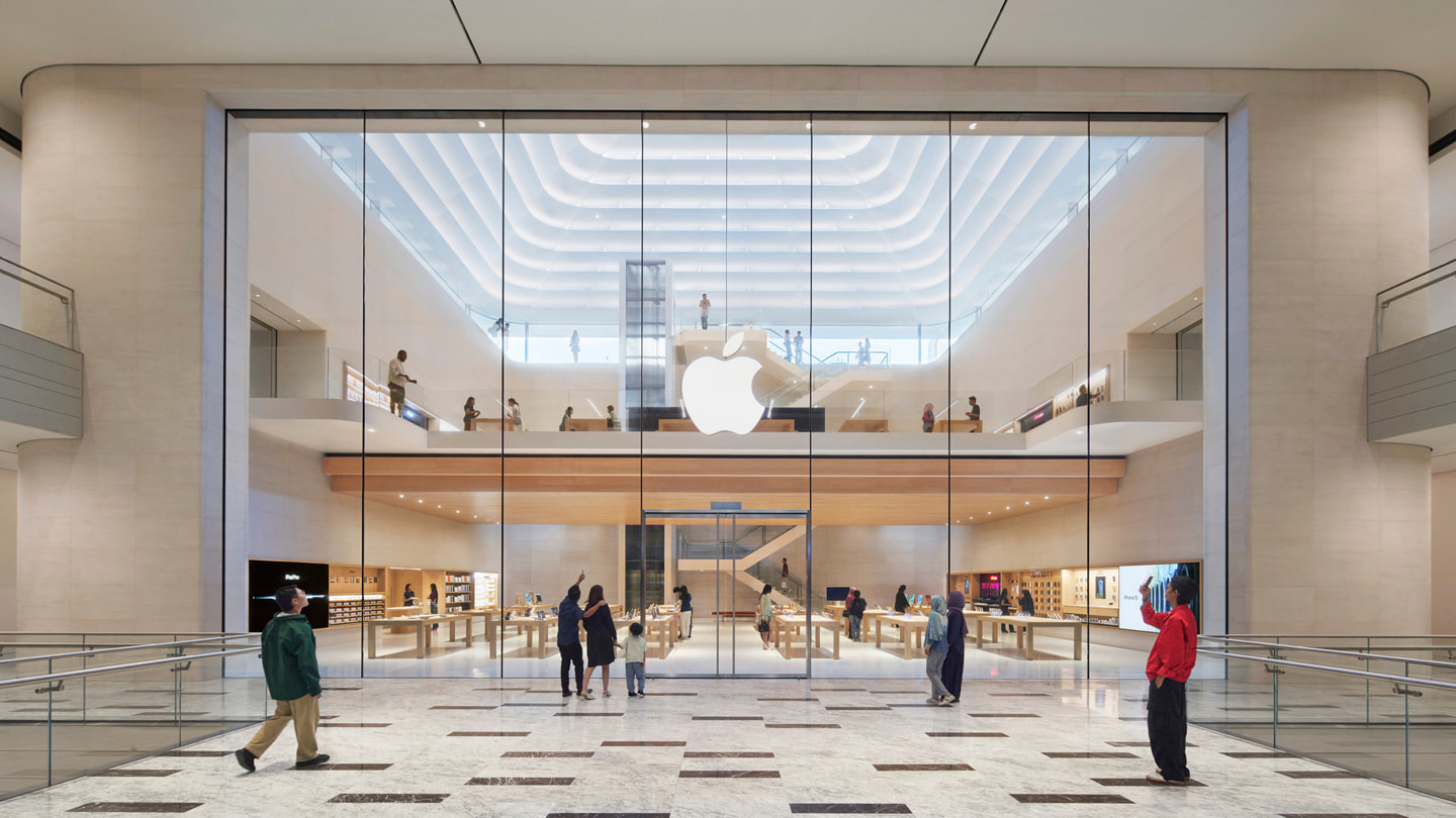 Imagen de varios clientes de pie frente a la entrada interior de Apple The Exchange TRX.