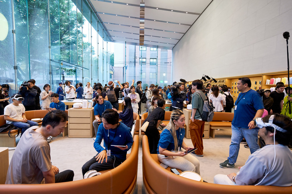 Powiększone ujęcie przedstawiające dziesiątki klientów i członków zespołu w ruchliwym sklepie Apple Omotesando.