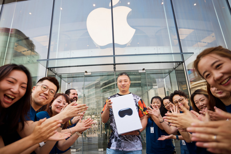 Team members cheer as a customer carrying an Apple Vision Pro box leaves Apple Wangfujing.