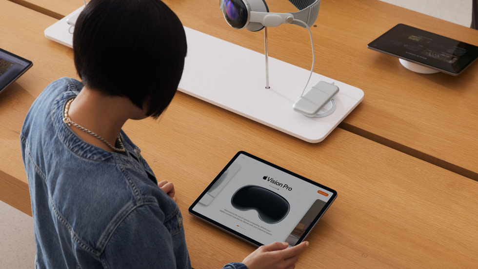 Une cliente regarde l’Apple Vision Pro sur un iPad dans un Apple Store.