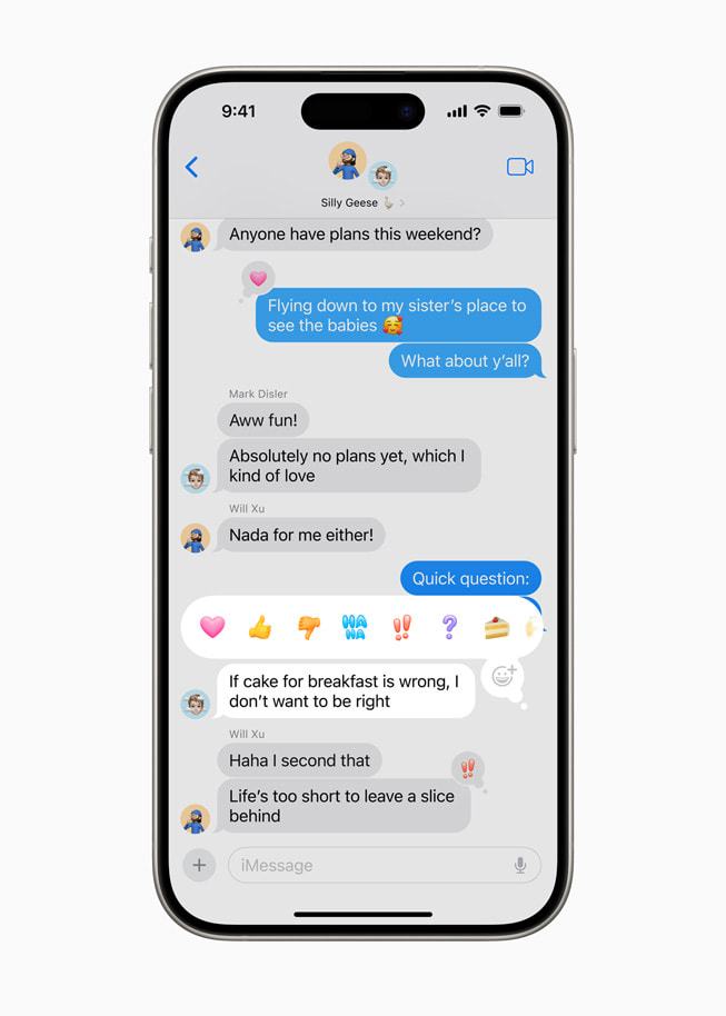 Un iPhone 15 Pro che mostra un iMessage selezionato con varie opzioni Tapback, fra cui un cuore, un pollice alzato, un pollice verso, una risata, un punto esclamativo, un punto di domanda e l’emoji di una torta.