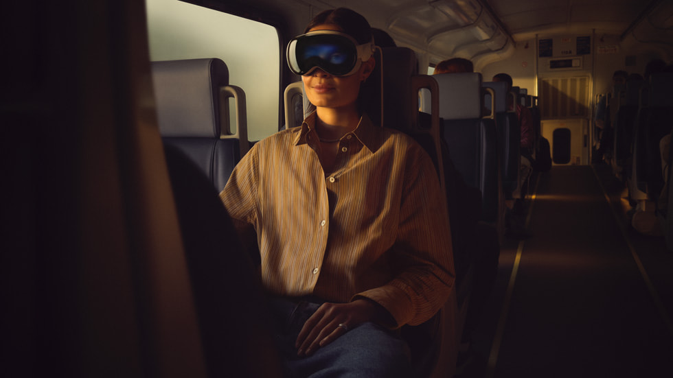 Seseorang memakai Apple Vision Pro di kereta api.
